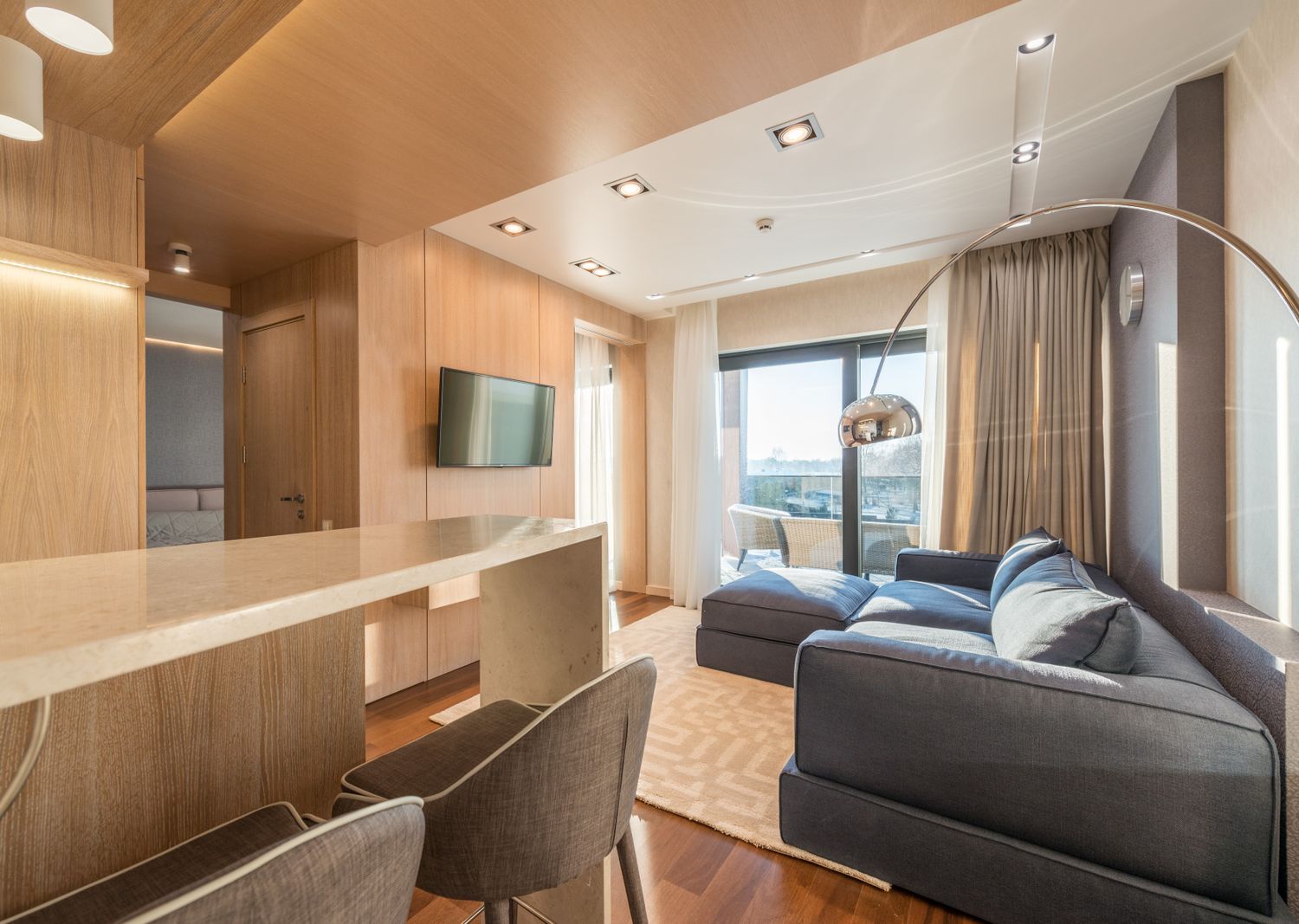 Séjour contemporain d'une résidence Apogée, boiseries claires et baie ouverte sur la loggia au douzième étage