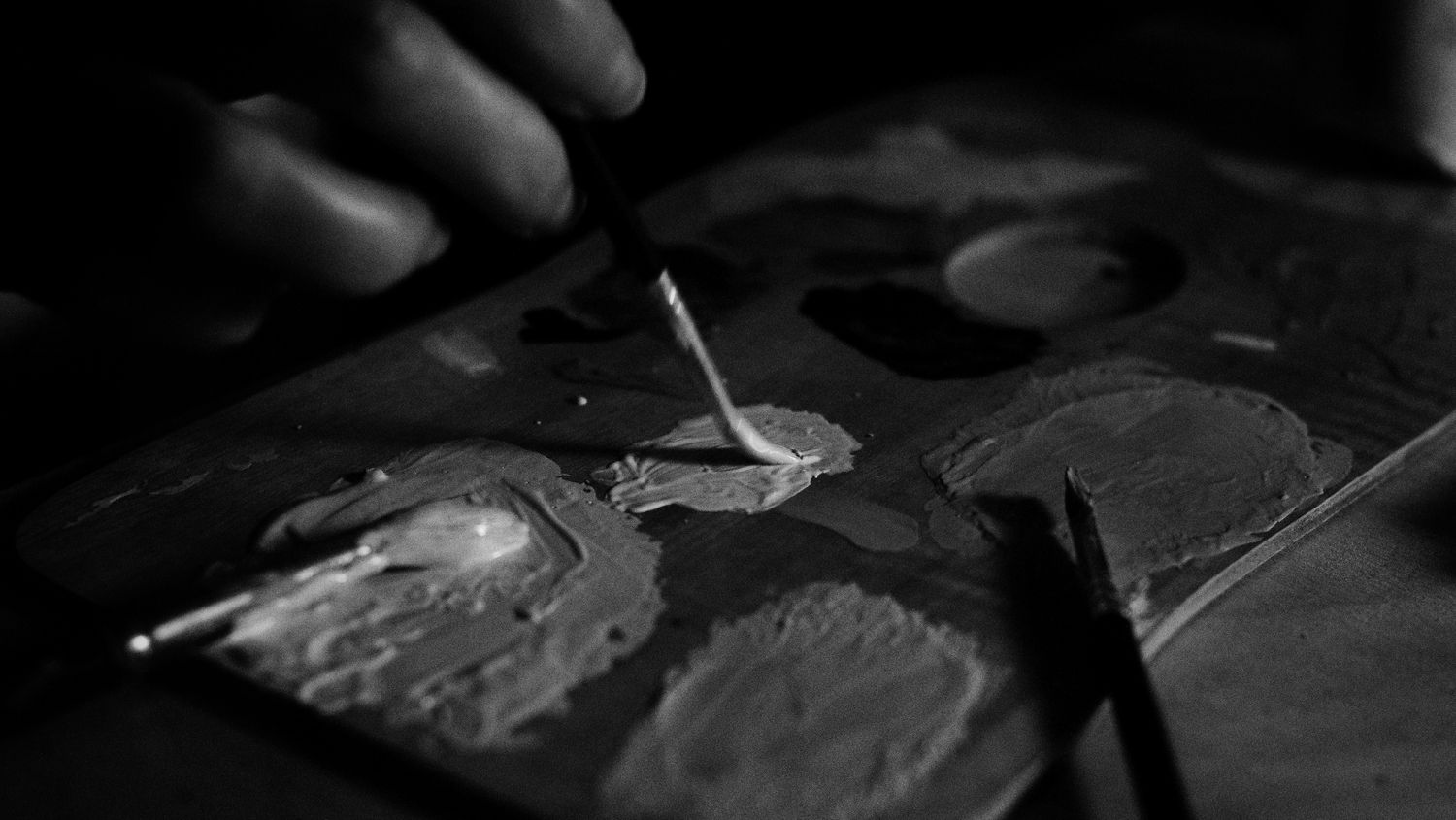 Palette de peintre en noir et blanc, couteau et pinceaux dans la matière
