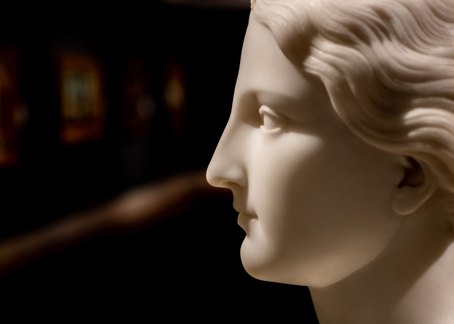 Buste de marbre blanc de profil, éclairé au projecteur dans la pénombre de la salle