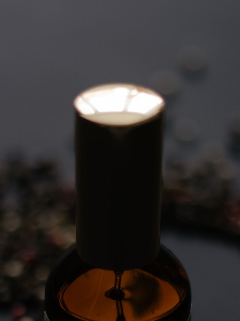 Bouchon doré d'un flacon de parfum, seul point de lumière dans la pénombre