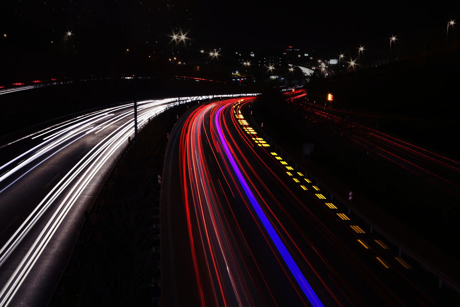 Filés de lumière blancs, rouges et bleus sur une autoroute la nuit, longue pose