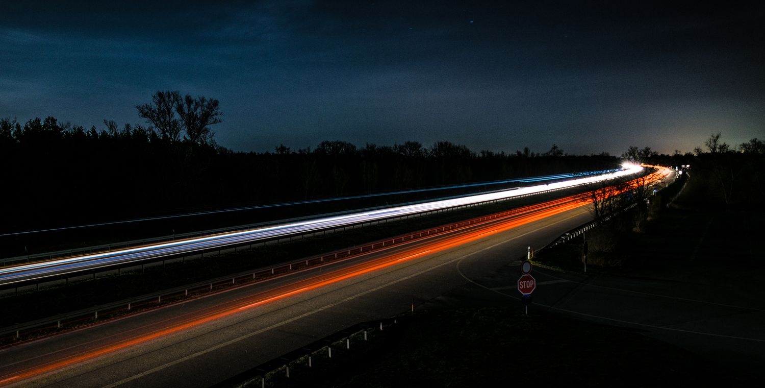 Trainée de lumière unique laissée par une voiture sur une autoroute au crépuscule, longue pose