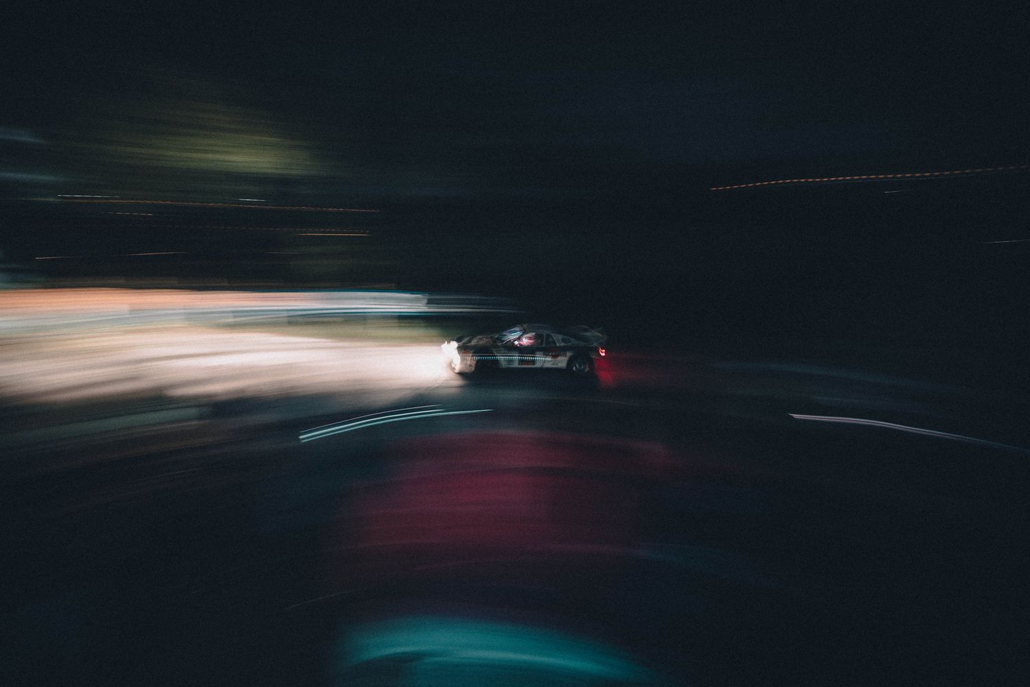 Voiture filant dans la nuit, silhouette floue et phares en filé